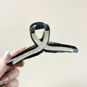 Détail de la grande pince à cheveux noire avec strass dorés pour cheveux épais