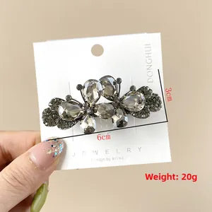 Détail de la pince à cheveux papillon en strass gris fumé sur carte de présentation