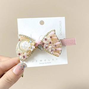 Close-up of elegant hair clip with pink crystals, white pearls and floral details