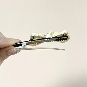 Detailed macro view of vintage gold alloy hair clip with pearls and emerald rhinestones