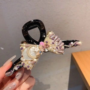Detailed shot of bow hair claw clip with pearls, rhinestones and pink resin flower