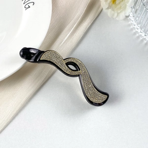 Dettaglio dell'elegante fermaglio a banana nero con motivi ondulati in strass