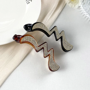 Eleganti fermagli a banana con strass neri e ambra con design ondulato e glitterato