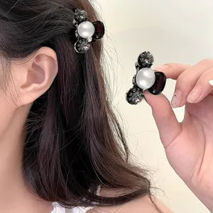 Detailed close-up of mini hair claw clip featuring large pearl and sparkling grey rhinestones