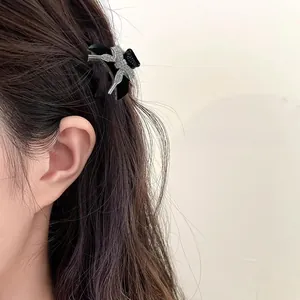 Close-up of a black bow hair claw clip with silver rhinestones on a model hairstyle