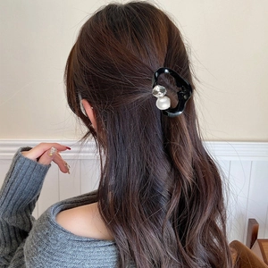 Close-up of elegant black mini hair claw clip with pearl and rhinestone on hair