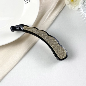 Dettaglio del fermaglio per capelli a banana con strass brillanti ed eleganti bordi dorati
