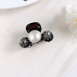 Close-up of mini resin hair claw with centered pearl and sparkling rhinestones
