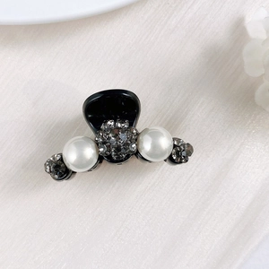 Close-up of mini hair claw with elegant pearls and smoky grey rhinestones on black resin