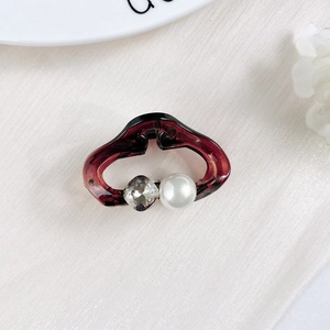 Close-up of tortoise shell mini hair claw with pearl and crystal on white fabric