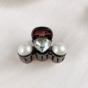 Close-up of a mini hair claw clip featuring heart-shaped crystal and white pearls decoration