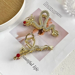 Detailed view of gold dragon hair claws with white rhinestones and red bead accents
