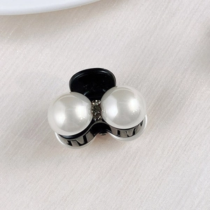 Detail shot of mini pearl and rhinestone hair claw clip on soft beige satin background