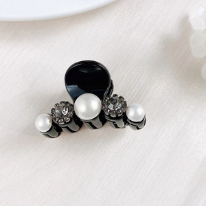 Close-up of a mini black claw clip with elegant pearls and sparkling rhinestones