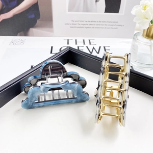Detail of marble cloud hair claw and geometric patterned clip with gold-tone hardware