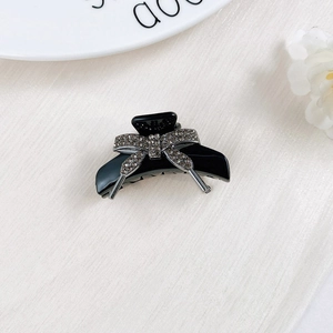 Detailed close-up of a black hair claw clip featuring a sparkling rhinestone bow design