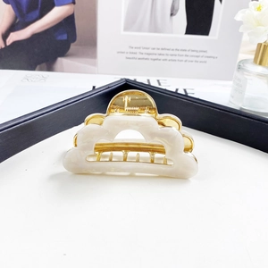 Detailed macro view of white marble acetate cloud hair claw with gold metal spring