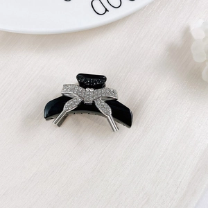 Detail of elegant black hair claw clip with silver rhinestone bow knot design