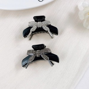Detail of mini bow hair claws with sparkling rhinestones on black resin base