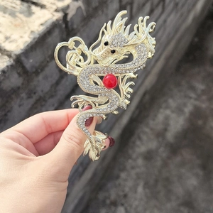 Macro detail of golden dragon hair claw clip with white rhinestones and red bead