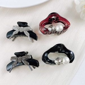 Detailed view of mini claw clips with pearls and rhinestones on soft fabric background
