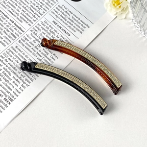 Dettaglio di strass scintillanti su fermagli a banana neri e ambra per capelli folti