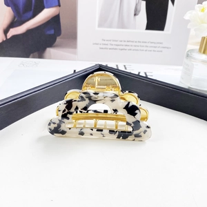 Close-up of elegant cloud-shaped hair claw clip with tortoise marble pattern and gold metal