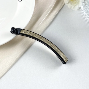 Dettaglio del fermaglio a banana elegante con strass lucidi e base dorata decorativa