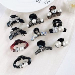 Detailed view of mini hair claws featuring pearls and rhinestones on white fabric