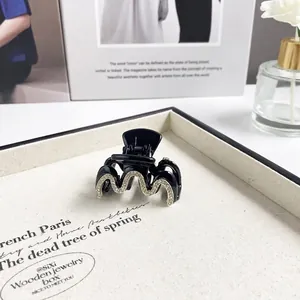 Eleganter schwarzer Haarclip mit Strasssteinen auf einem hochwertigen hellen Tablett