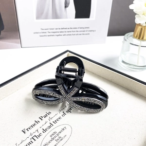 Eleganter schwarzer Haarklammer mit Strass-Infinity-Design auf beigem Tablett-Hintergrund