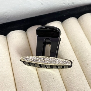 Detail of elegant black hair claw clip featuring double-row rhinestones and gold-tone base