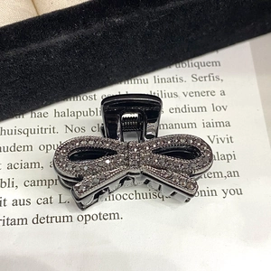 Makroaufnahme von dunklen Strasssteinen auf schwarzem Schleife-Haarspange-Metall
