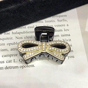 Detail einer schwarzen Haarklammer mit einer funkelnden goldenen Schleife aus Strass