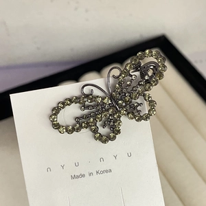 Detailed view of butterfly hair clip with olive green rhinestones on black alloy base