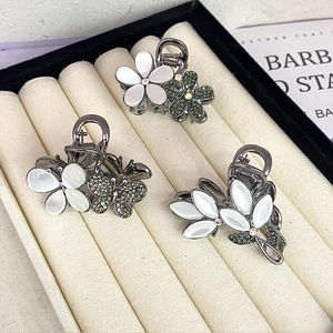 Three-piece metal hair claw clips with opal flowers and green rhinestones in a tray