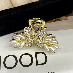Nahaufnahme der goldenen Schmetterling-Haarklammer mit weißen Perlen und glänzenden Strass