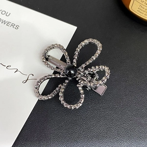 Detail of flower shaped alloy hair clip with grey rhinestones and black center bead
