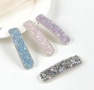 Close-up of four luxury crystal hair clips in blue pink purple and silver colors
