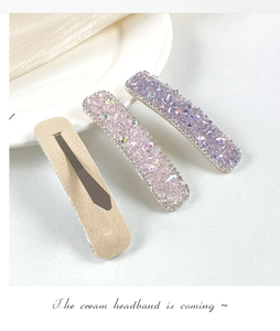 Macro shot of pink and purple crystal-studded hair clips with shiny rhinestone edges