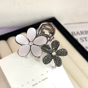 Macro detail of elegant double flower hair claw with opal petals and green rhinestones