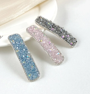 Close-up of three rectangle hair clips in blue, pink, and grey with sparkling crystals