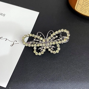 Detail of a butterfly hair clip featuring champagne rhinestones on a silver metal base