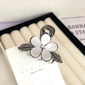 Detail of floral hair claw clip with shell petals and rhinestones on a card
