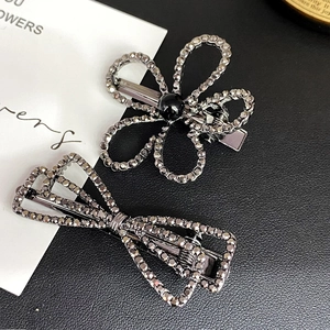 Close-up of grey crystal flower and bow hair clips set with elegant alloy finish