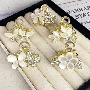 Detail of five mini gold hair claws with opal flowers and rhinestones in a beige jewelry box