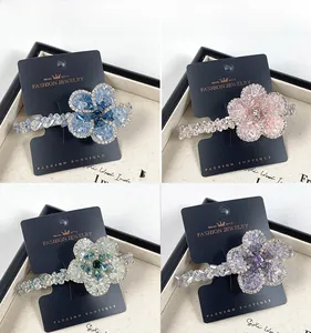 Détail de barrettes fleurs avec cristaux colorés en bleu, rose, vert et violet