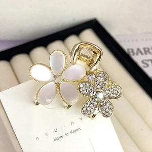 Close-up of golden flower hair claw with opal petals and sparkling zircon rhinestones