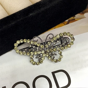 Elegant gunmetal butterfly hair clip with shimmering yellow rhinestones on dark velvet