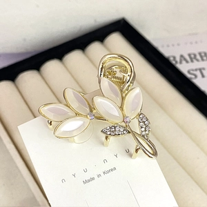 Macro detail of gold flower hair claw clip with opal stones and sparkling rhinestones